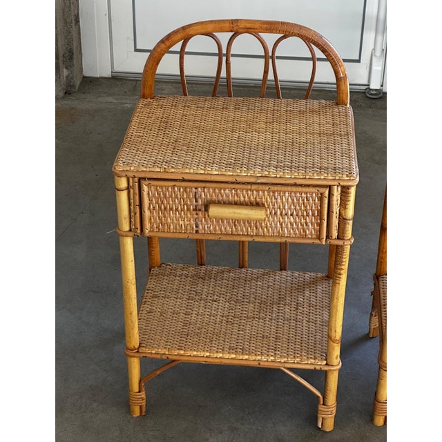 An elegant pair of vintage rattan and wicker bedside tables dating from the 1970s. Their light silhouette, with curved...