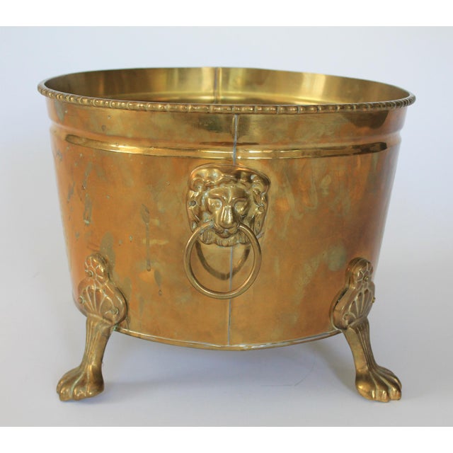 Vintage oval brass cachepot with lion head handles, paw feet and etched Asian motif. Made in Hong Kong. One rivet is loose...