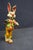 Hand-painted folk art rabbit figure dating to the 1950s, depicted standing upright in a red-and-cream striped shirt, green...