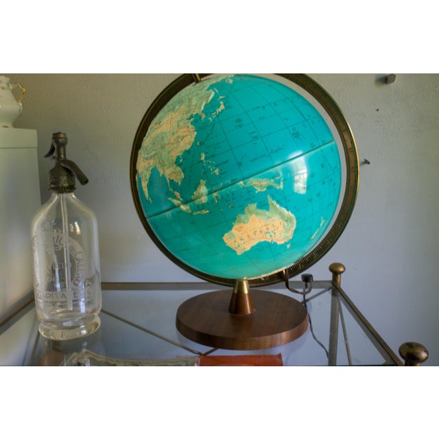 A stunning mid-century illuminated topographic globe that doubles as a table lamp. Warm walnut base, brass meridian ring,...