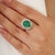 Make an unforgettable impression with this striking 5.2 CTW Emerald and Diamond Halo Ring, masterfully crafted in solid...