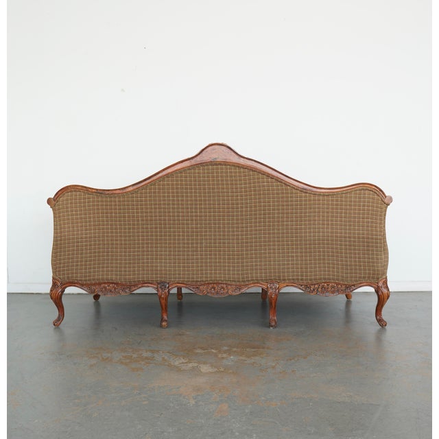 This Louis XV–style sofa features a gracefully contoured silhouette with a richly carved wooden frame, detailed with a...
