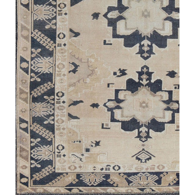 Handwoven in Turkey, this vintage Oushak rug features three large medallions in navy blue color. The repeating medallions...