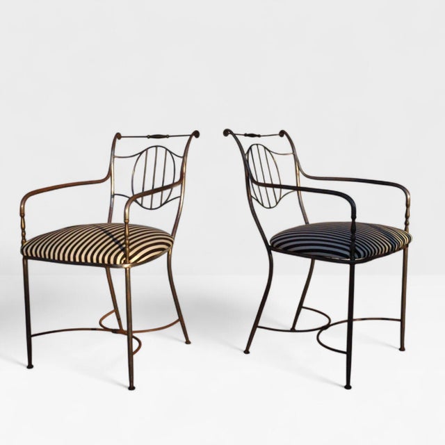 A pair of mid-20th century iron garden armchairs executed in the neoclassical style and reminiscent of the work of Maison...