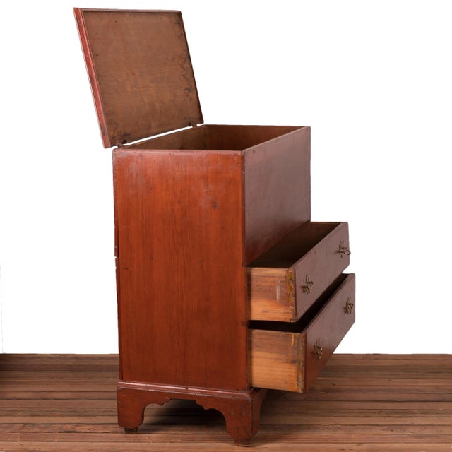 A New England mule chest, 19th century. Pine with red wash, moulded lid and drawers, solid bootjack ends with attached...