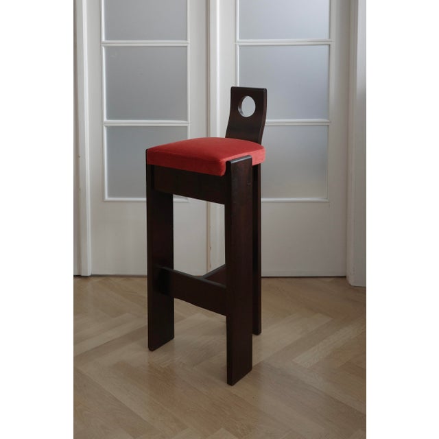 Bar stools from solid wood in brutalist style with a dark wooden construction are complemented by newly reupholstered...