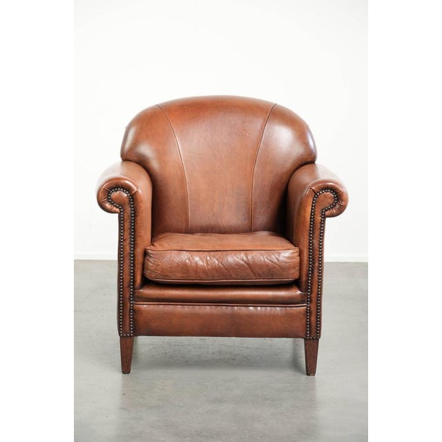 This vintage sheepskin armchair with a comfortable seat and finished with decorative studs. : This vintage sheepskin...