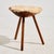Handcrafted milking stool with three legs and a sheepskin-covered seat. The surface shows scratches and wear in places.