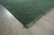 A 6' x 9' hand-knotted wool rug with a plain moss green Lori Baft (Gabbeh style) field, softly striated in tone, with...