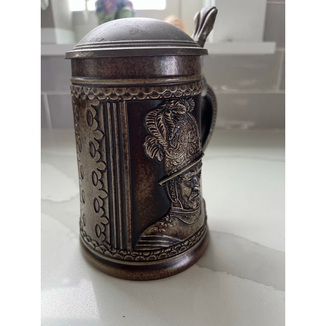 Beer stein with pewter lid made in West German by Gerz. Soldier depicted on the side with a brown glaze. The inside and...