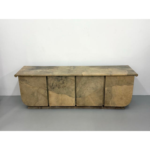 A striking vintage postmodern sideboard clad in lacquered dyed goatskin parchment, showcasing an organic patchwork design...