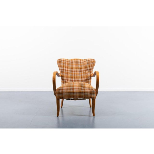 Mid-Century Modern sculptural armchair from 1950s. Frame in varnished birch, upholstered in original striped brown fabric....