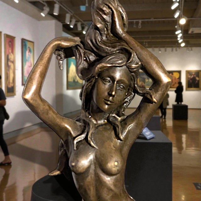 A cast bronze effigy of a mythological mermaid. It is signed "Harriet", near the bottom of the figurine, in a replica of...