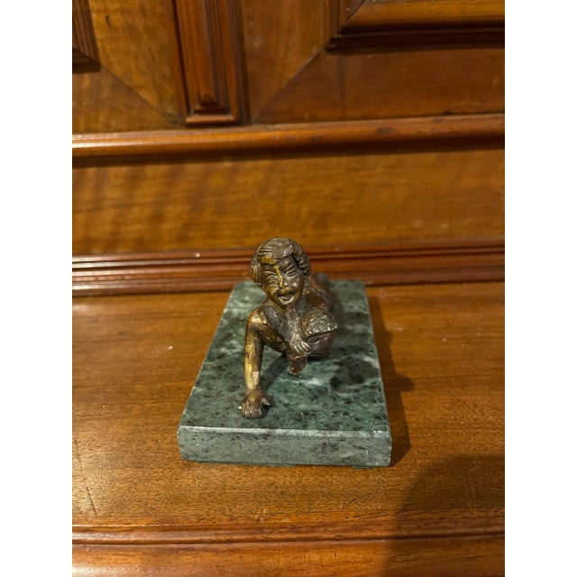 Lost wax cast bronze statue depicting a recumbent boy holding a bird mounted on a green rectangular marble base. Would...