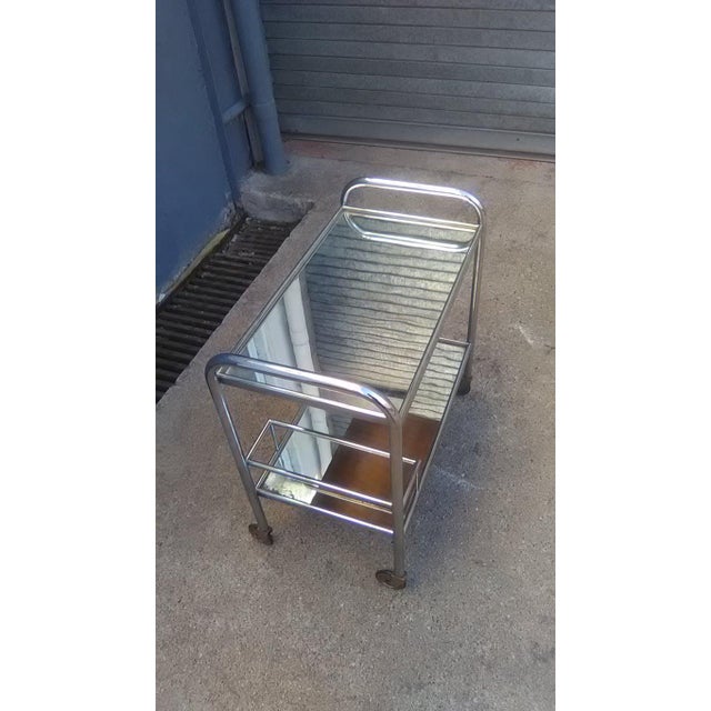This small serving bar cast stands on wheels and is made of chromed metal with a mirror top.