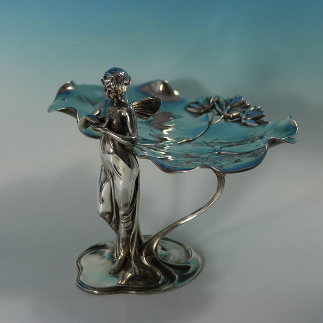 WMF Art Nouveau visiting card tray decorated with a fairy standing before two large lily leaves, holding a dove in her...