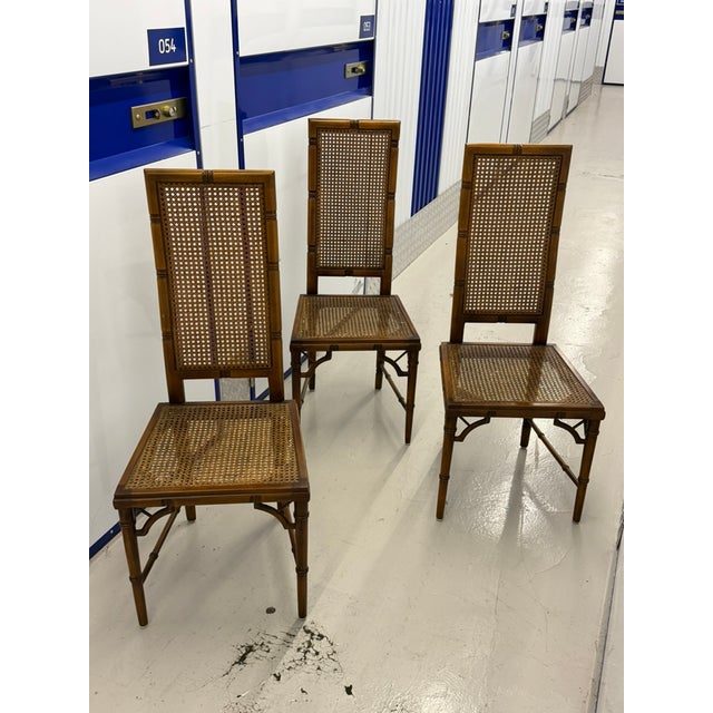Set of three vintage Hollywood Regency dining chairs in stained faux-bamboo wood, with caned backs and caned seats,...