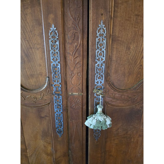 A beautifully hand-crafted 19th-century French Provincial armoire featuring richly figured solid wood, hand-carved floral...