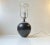 A delicately executed ceramic table lamp in black glaze with white stripes at the top and bottom. This shape is commonly...