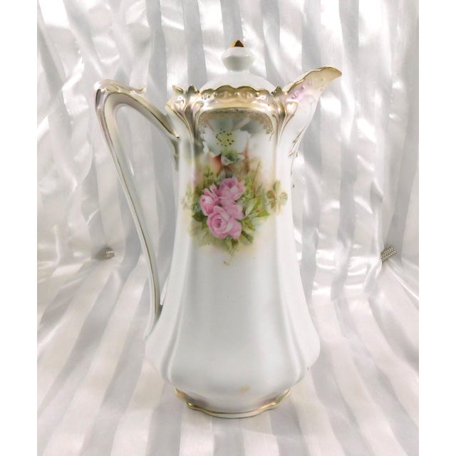 This is a white Reinhold Schlegelmilch RS Prussia chocolate pot with pink flowers and greener and a metallic gold sheetn...