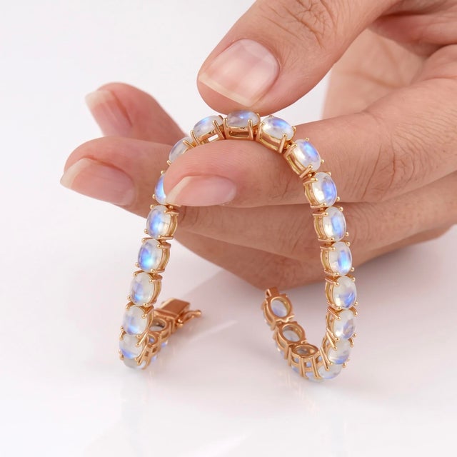 A mesmerizing tennis bracelet featuring a continuous row of oval moonstone cabochons set in warm gold-tone sterling...