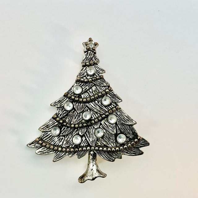 A lovely Christmas Brooch from the 1980s. It features a Christmas Tree in a silver metal with a black wash that resembles...