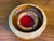A distinctive vintage studio pottery ashtray featuring a sculptural circular form, warm earth-tone stoneware body, and...