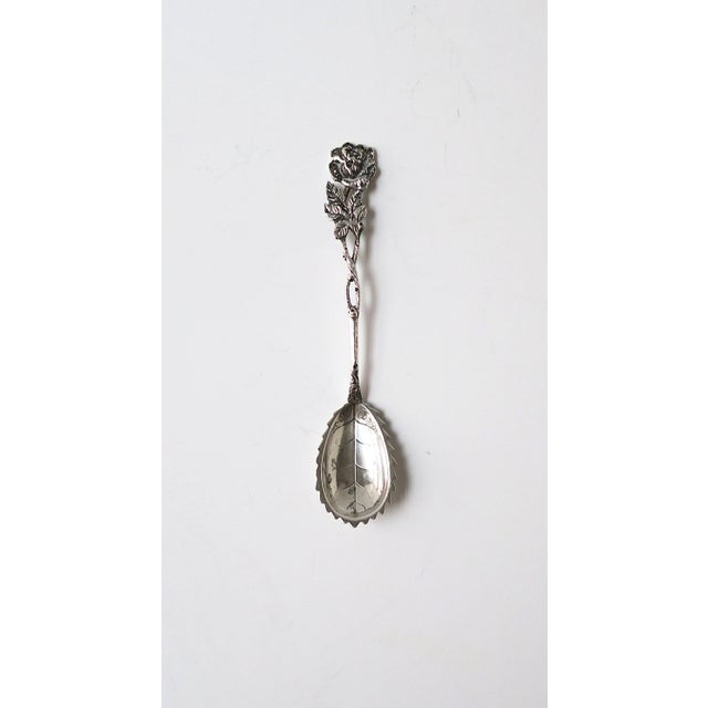 A sterling silver spoon with a rose‑flower botanical design, Victorian period, circa turn‑of‑the‑century (1890–1910),...
