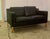 A classic Danish Modern two-seater sofa upholstered in black leather, resting on legs made from solid beech. With its...