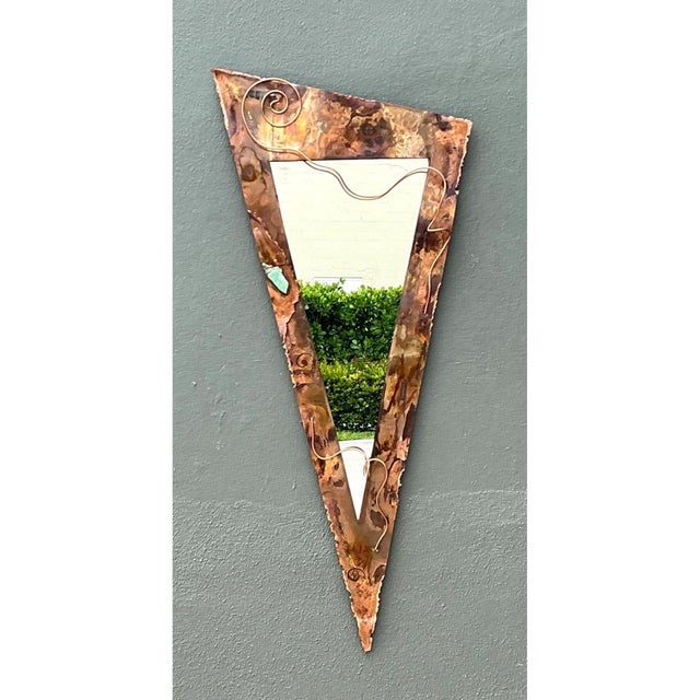 This wall mirror takes a bold, sculptural approach to form, its inverted triangular silhouette narrowing dramatically from...