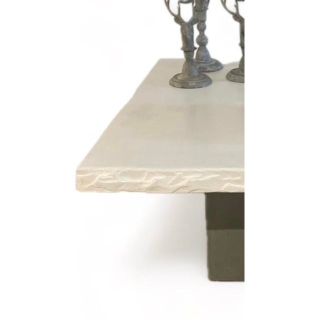 This contemporary coffee table features a concrete base in a grey / taupe color with a n off white 2.5" rough cut concrete...