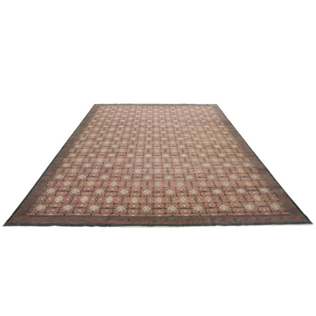 A Khotan wool rug In a peach-brown color field with interconnected rosette designs. This hand-knotted modern piece has...