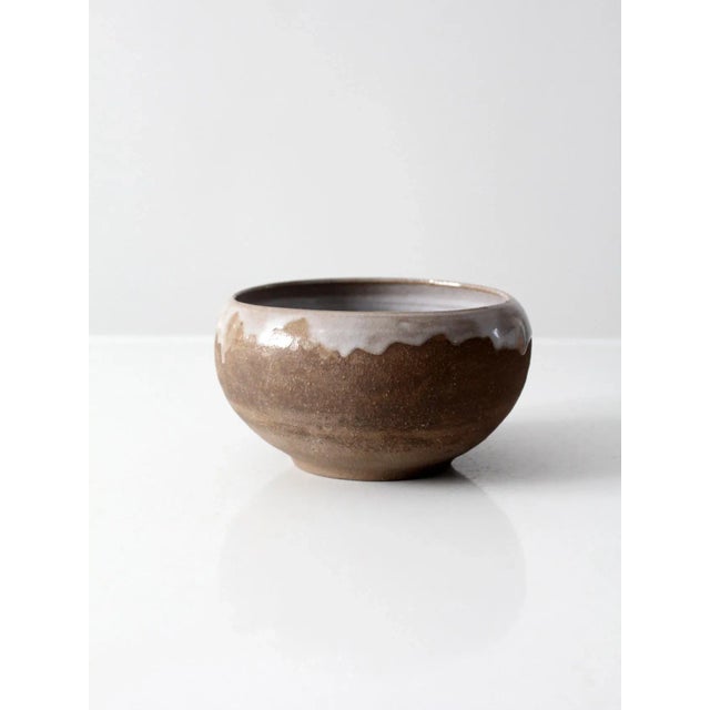 A vintage studio pottery bowl with a hand-crafted form, featuring an unglazed exterior and a light gray glazed interior....