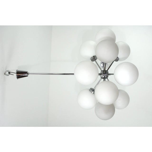 Chrome-plated brass frame, 12 matt white opal glass balls, 12 E14 sockets. This piece is attributed to the mentioned...