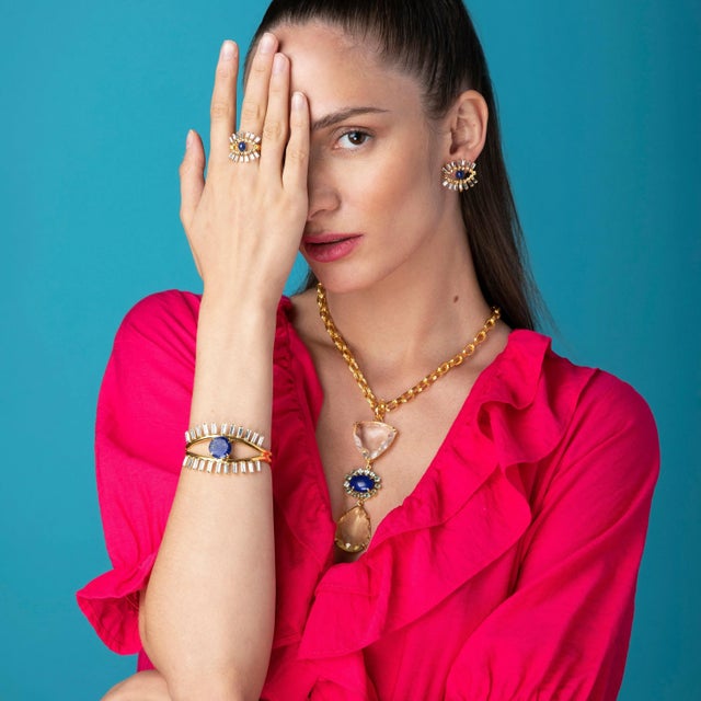 The Sabina Studs, expertly crafted from semi-precious stones, feature a unique eye design with multiple contrasting...