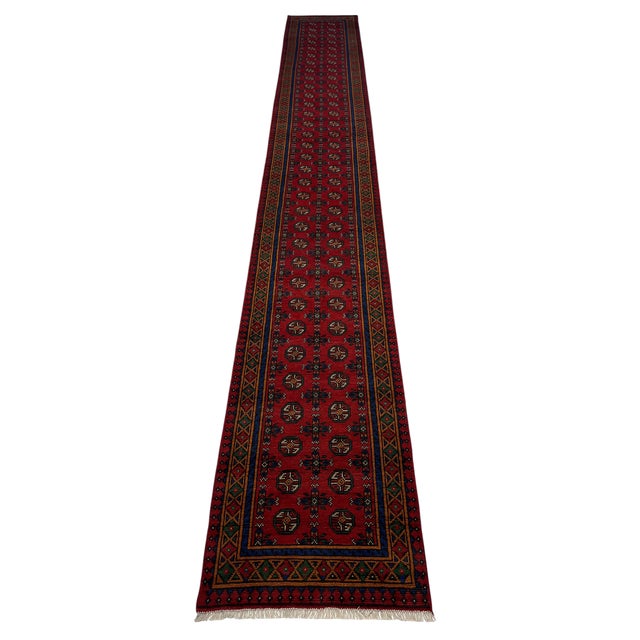 This extra-long wool runner features two rows of repeating octagonal motifs across a rich red field. Navy blue, green,...