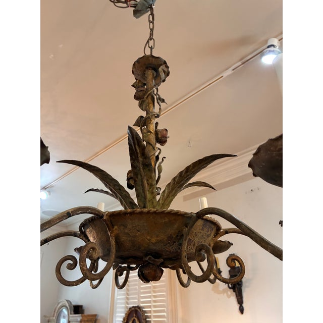 An elegant, six light Italian tole chandelier in a bronze and patinated gold paint finish. The hand-wrought fixture is...