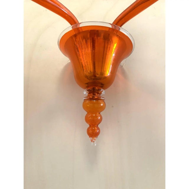 Contemporary translucent orange glass wall sconce in murano glass. decorated in translucent orange colour which makes it...