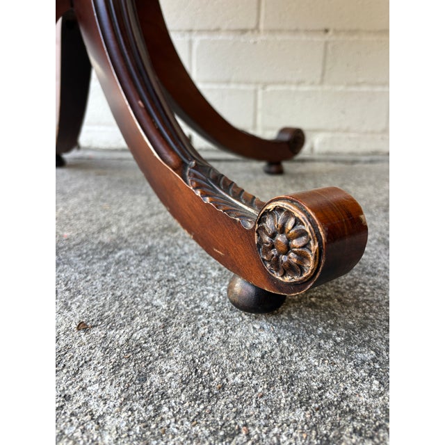 antique English Regency-style drum table is constructed from mahogany wood and features an octagonal leather top with gold...