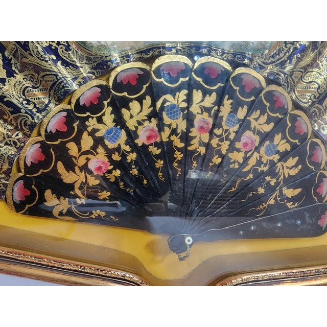 Beautiful lady's fan hand painted and framed to perfection. It shows daily family life scenes with an eye catching black...