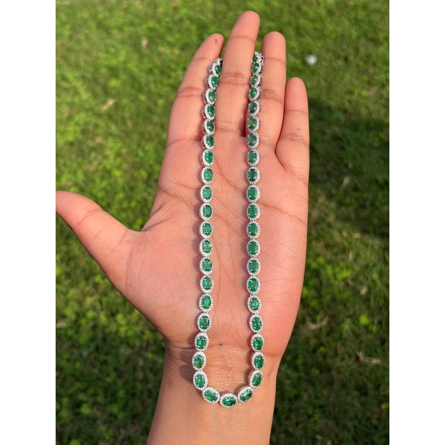This elegant oval emerald and diamond tennis necklace is crafted in 14k white gold and features a continuous line of oval-...