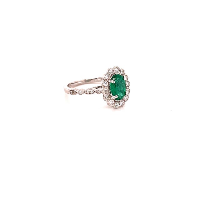 This ring has a 1.09 Carat Oval Cut Emerald and is surrounded by 28 Round Cut Diamonds that weighs 0.53 Carats. (Clarity:...