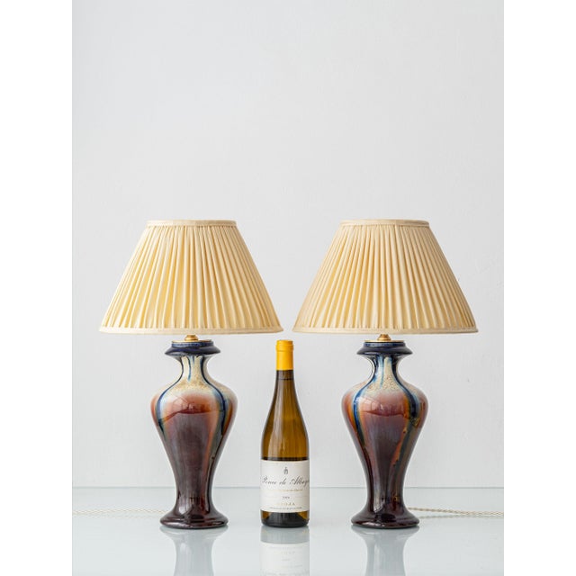 Glazed in a flowing flambé that pours from a cobalt-blue collar down through cream, oxblood, and chestnut into a deep...