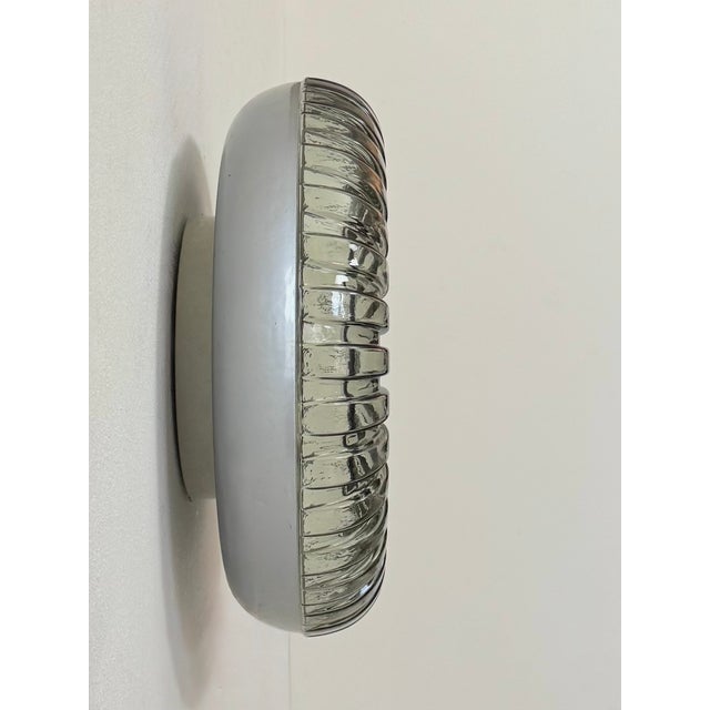 Murano pressed glass wall sconce with a central mirror-polished stainless steel disc, produced in Italy in the 1960s. An...