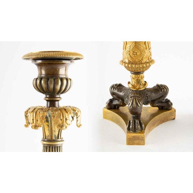 Elegant pair of French Empire-style candlesticks executed in finely chased gilt and patinated bronze. Each features a...