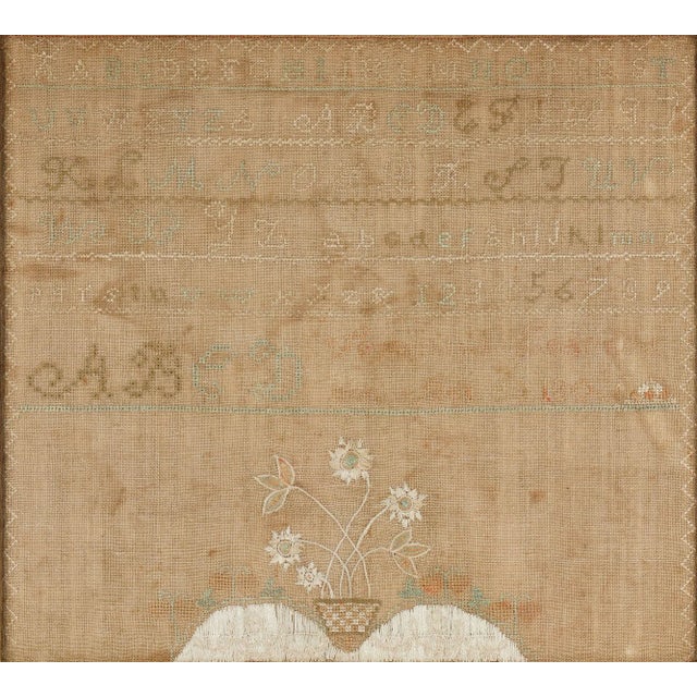 American needlework sampler of silk floss on linen with a modest zig-zag border framing an uppercase letter alphabet,...