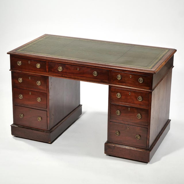 A nicely proportioned three-piece Georgian kneehole desk with a green tooled leather writing surface and gilt embossed...