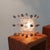 26 light-bulbs are stuck together like a cluster of bubbles. One light-bulb is connected to the power-source and burns....