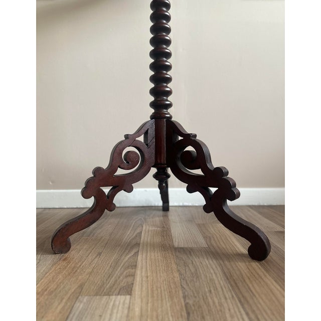 An elegant Victorian-era wine table, circa 1860, featuring a richly carved barley twist pedestal and a gracefully...