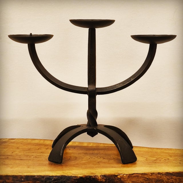 Three-light wrought iron candelabra, handcrafted using the hot-forging technique. The partially twisted central stem rests...